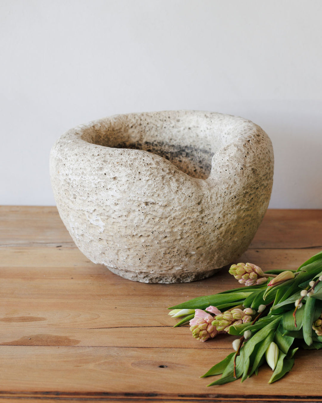 Rough pale bowl and pink hyacinths on a wooden table.