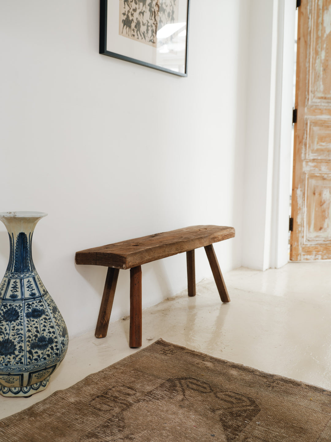 a blue and white vase sits next to a wooden bench