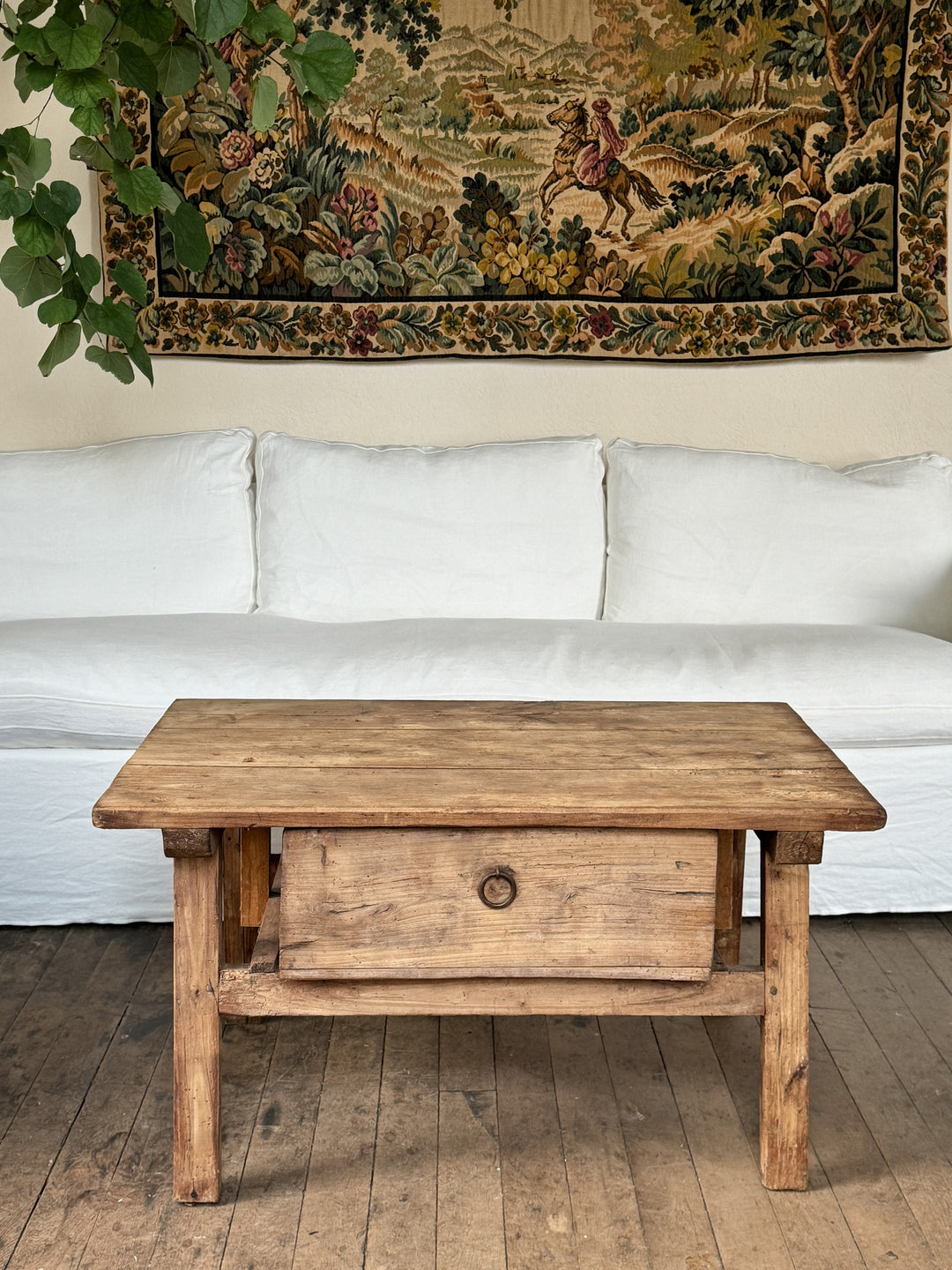 a wooden coffee table is sitting in front of a white couch in a living room .