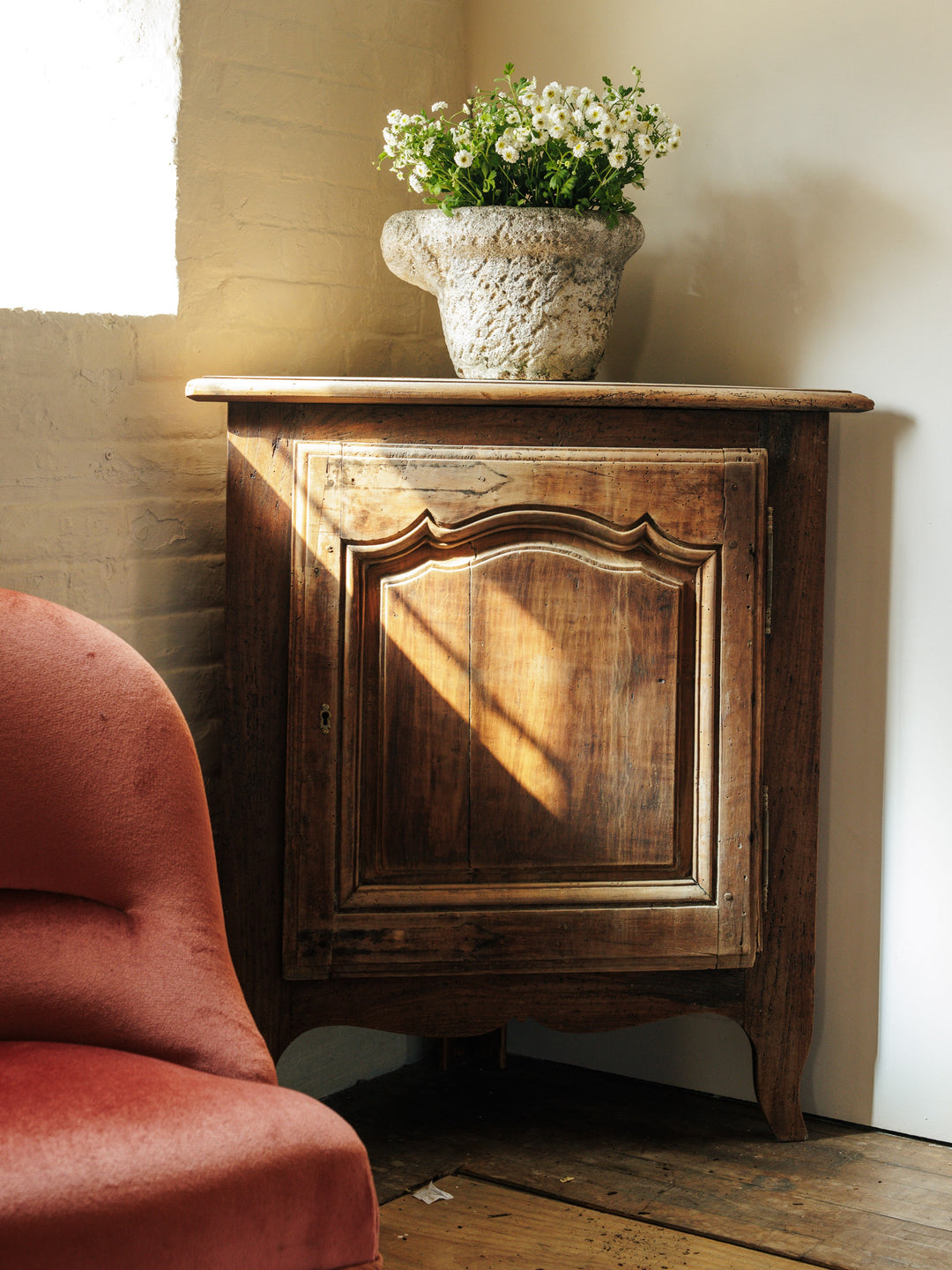 a wooden cabinet with a vase of flowers on top of it
