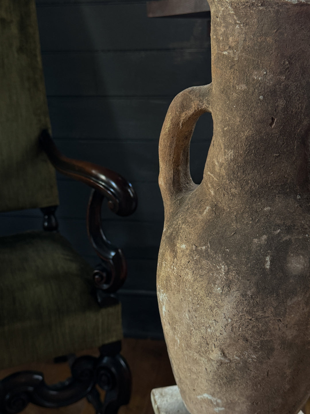 a large vase is sitting on a table next to a chair .