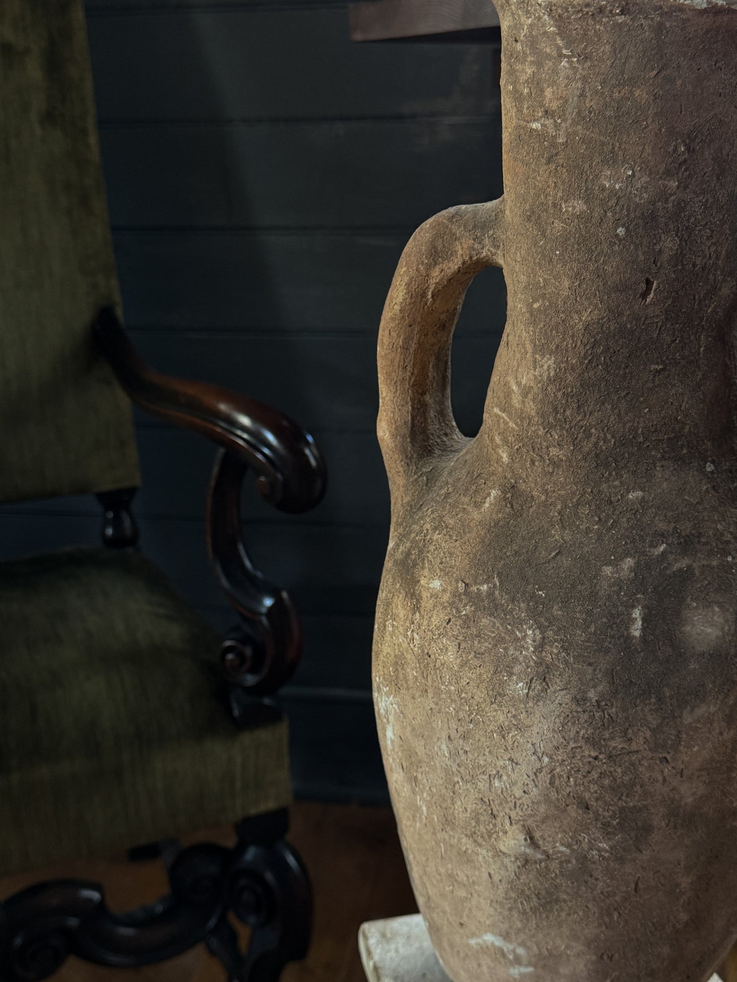 a large vase is sitting on a table next to a chair .