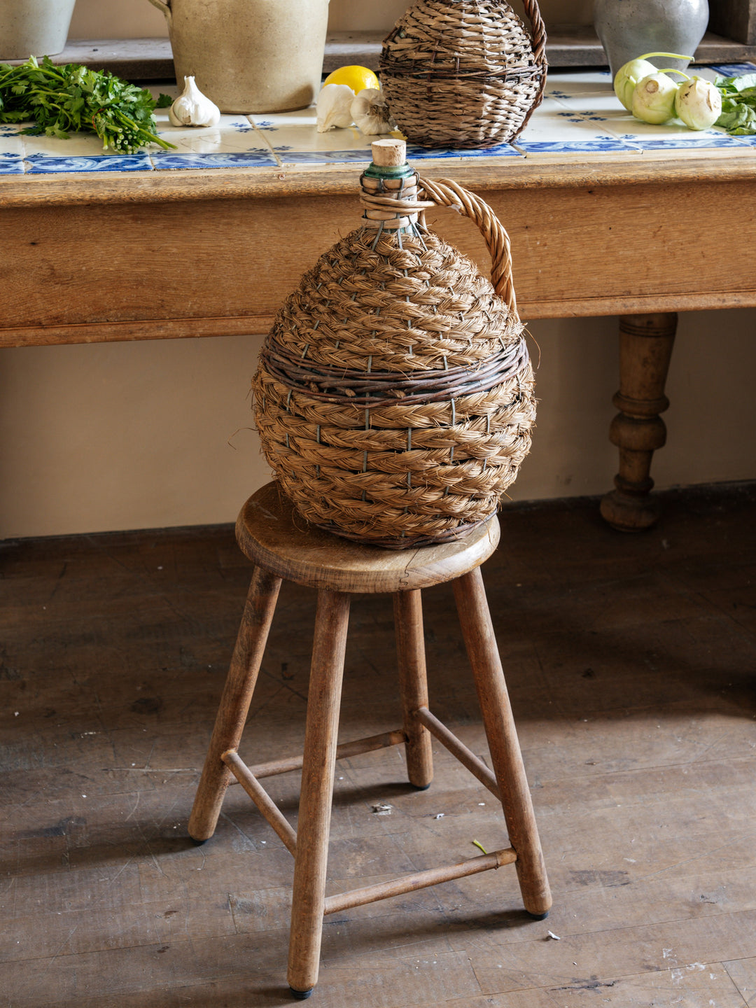 a wicker bottle is sitting on a wooden stool