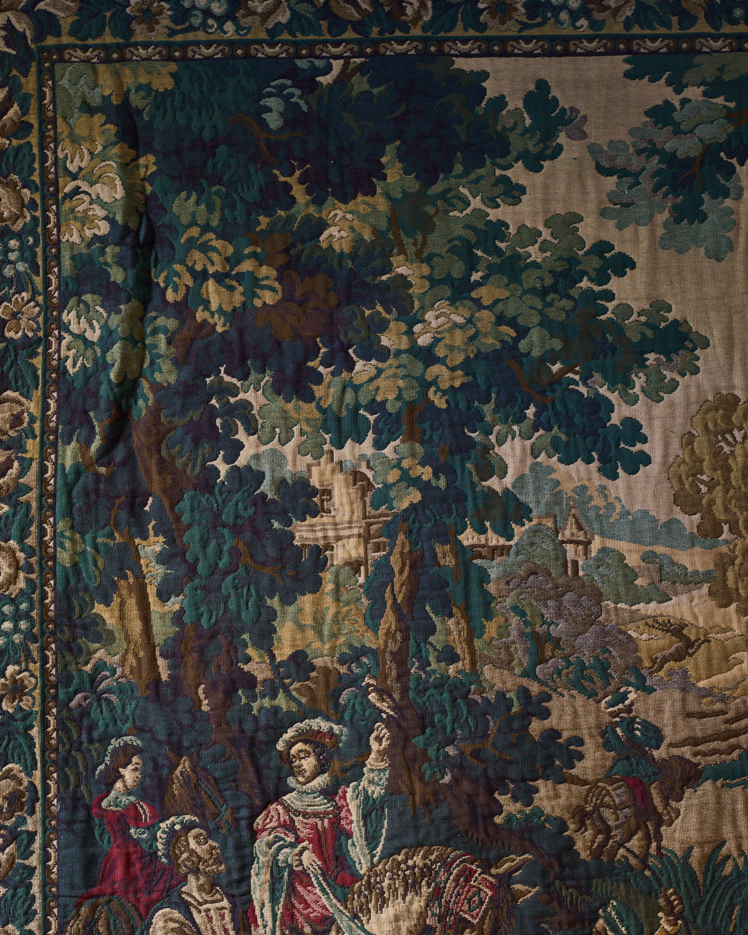 A tapestry depicting a forest scene with a castle, and figures in period clothing, one holding a bird.