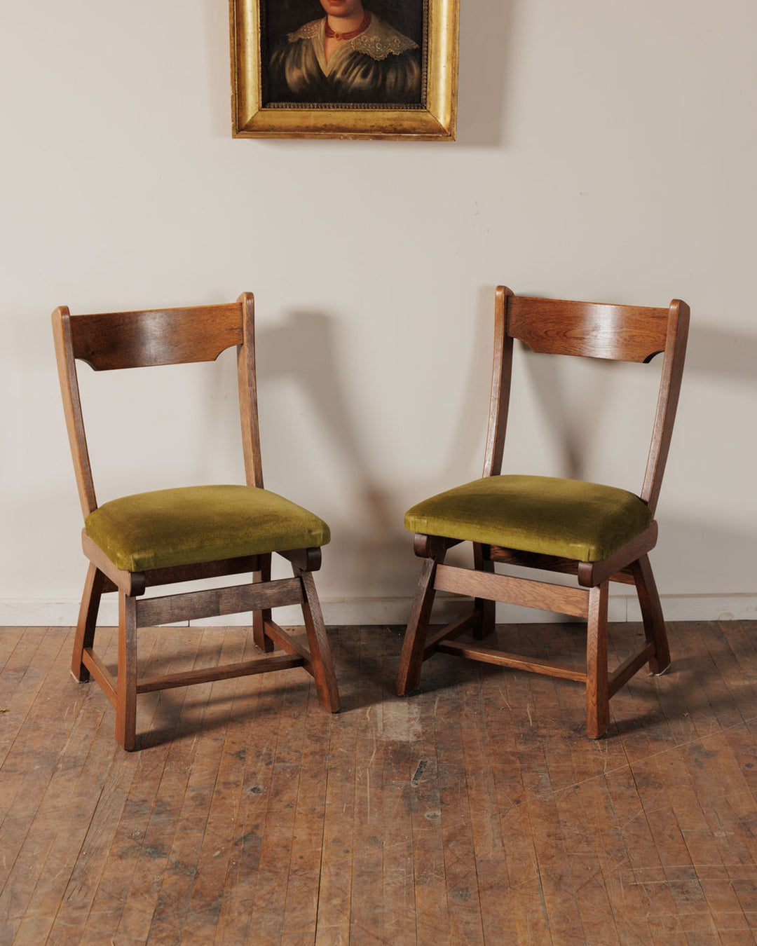 Pair of wooden chairs with olive green velvet seats.