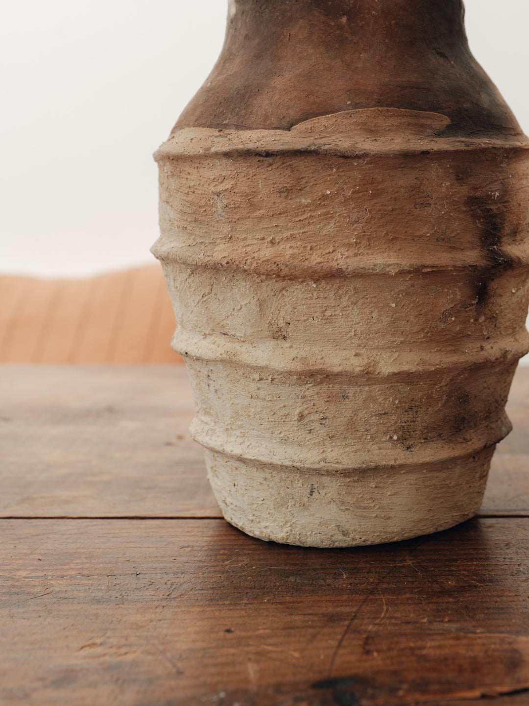 a clay vase is sitting on a wooden table .
