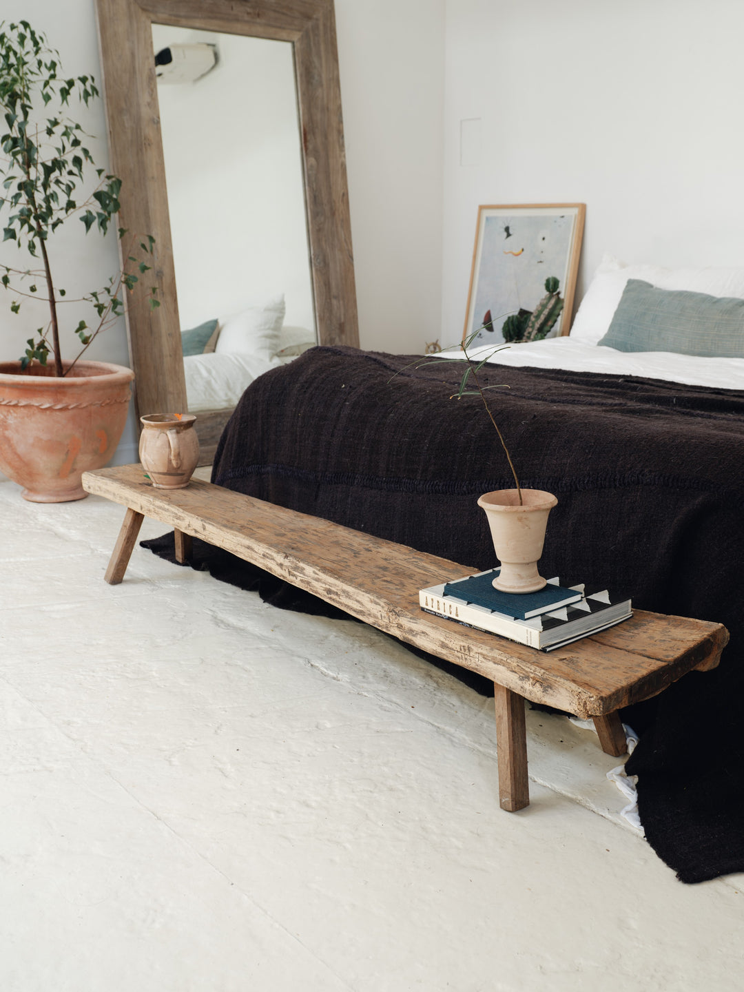 a wooden bench in a bedroom next to a bed .