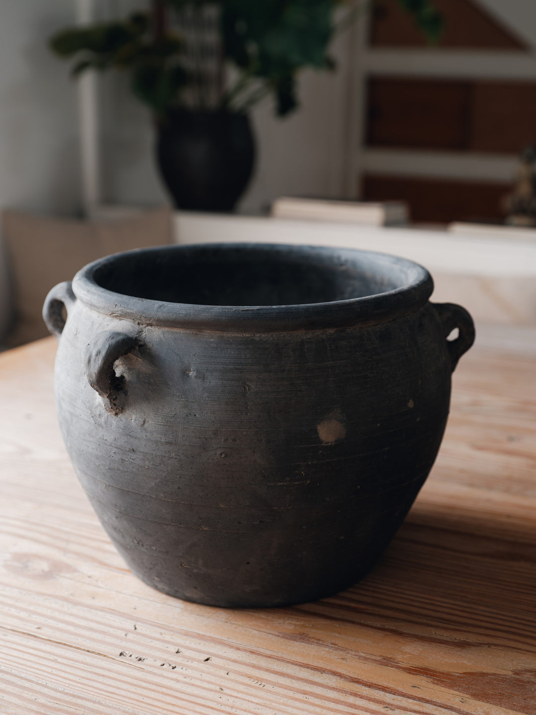 a black pot with two handles is sitting on a wooden table .