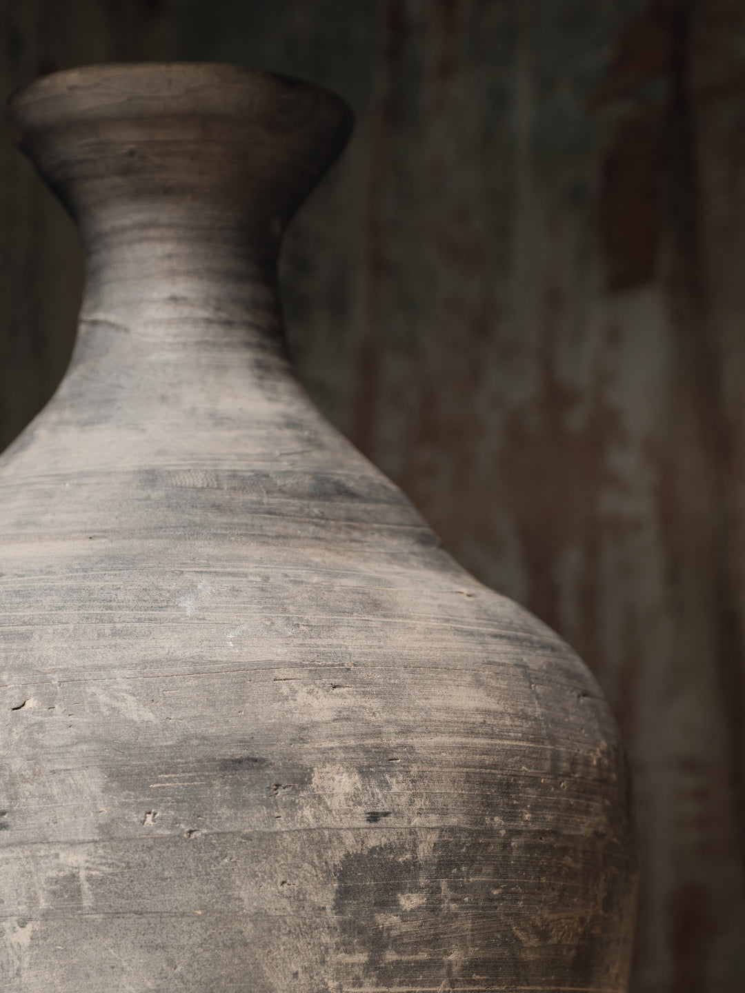a large clay vase is sitting on a wooden table .
