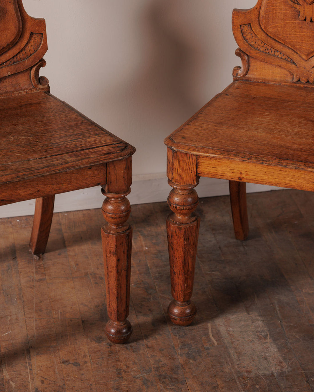 Two antique wooden chairs with turned legs and carved backs.