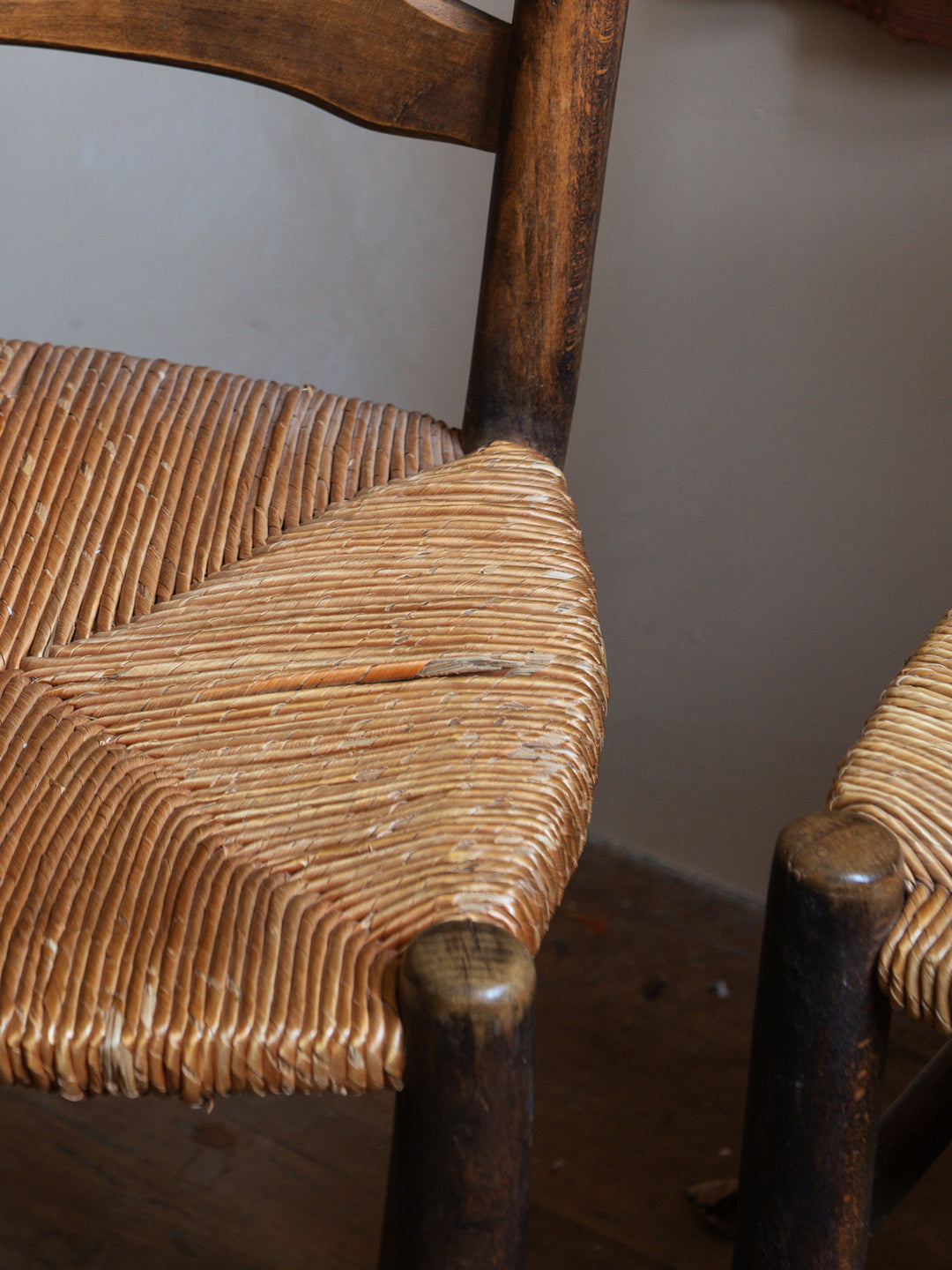 a wooden chair with a wicker seat sits on a wooden floor