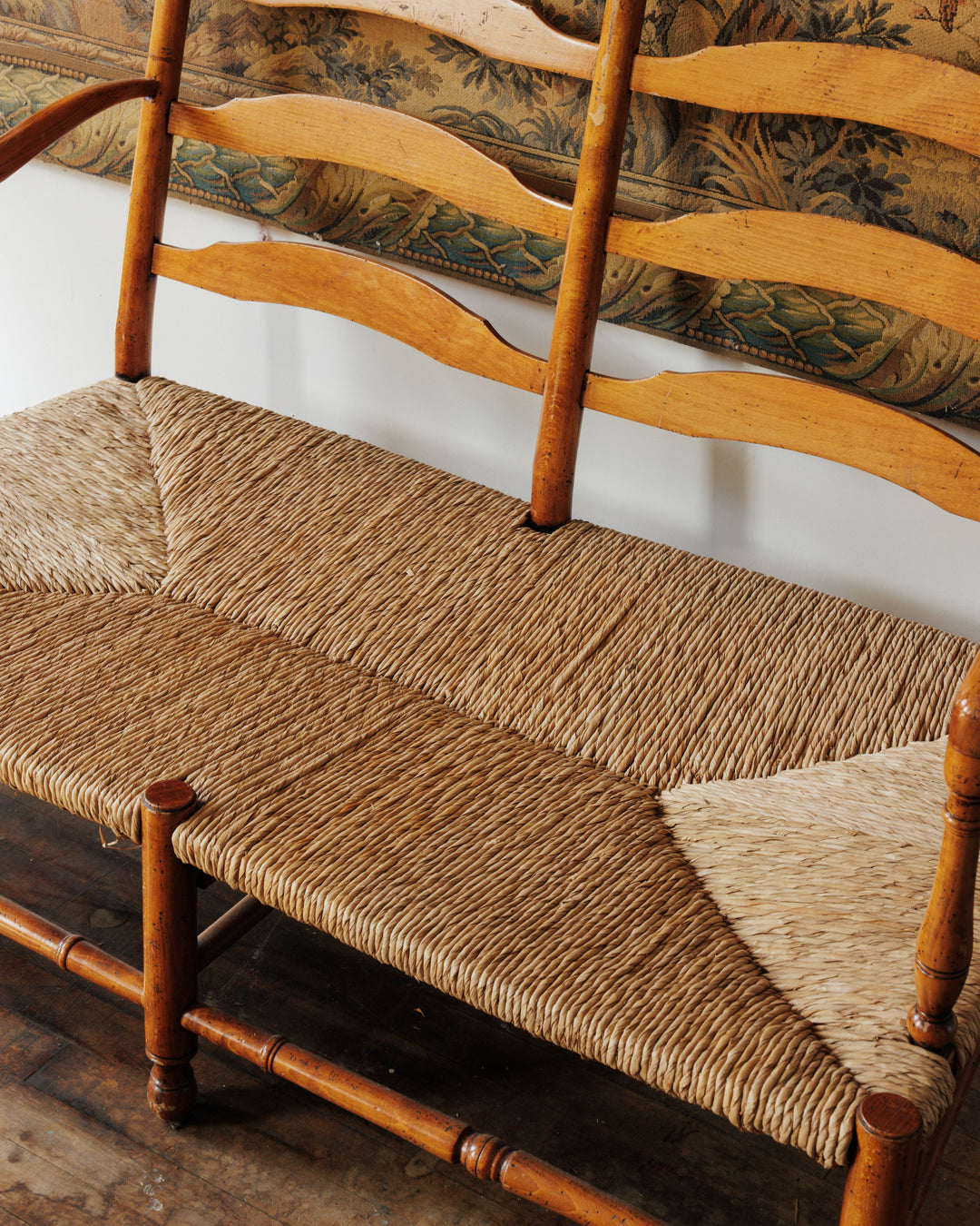 a wooden bench with a wicker seat sits on a wooden floor