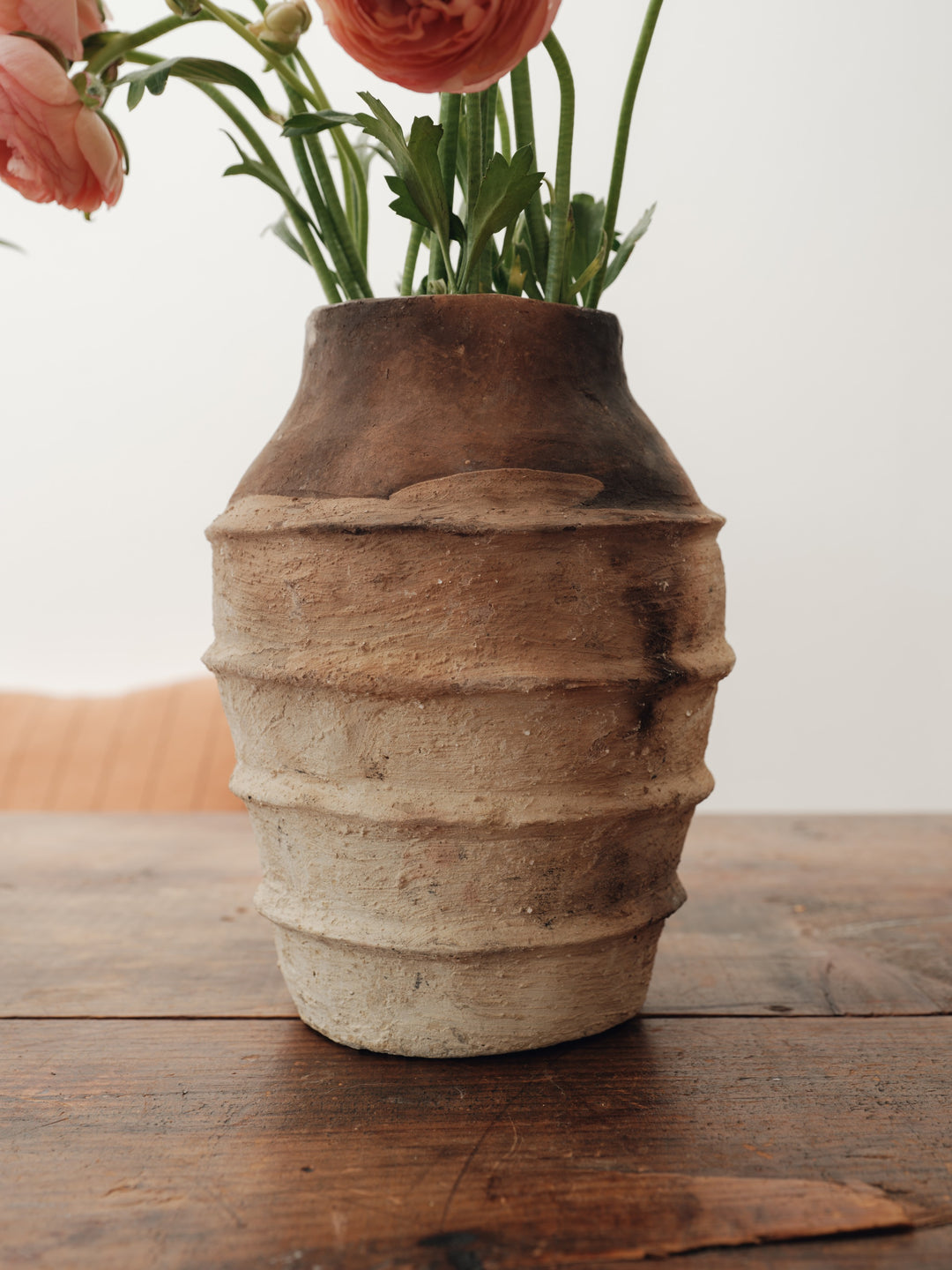 a vase with flowers in it is sitting on a wooden table .