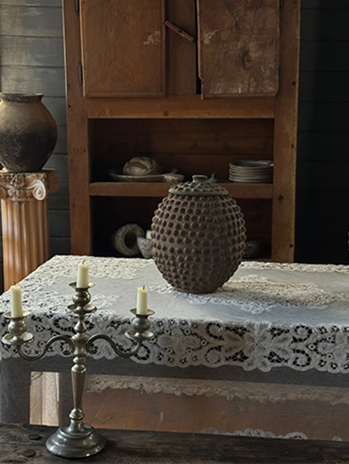a table with a lace tablecloth and candles on it .
