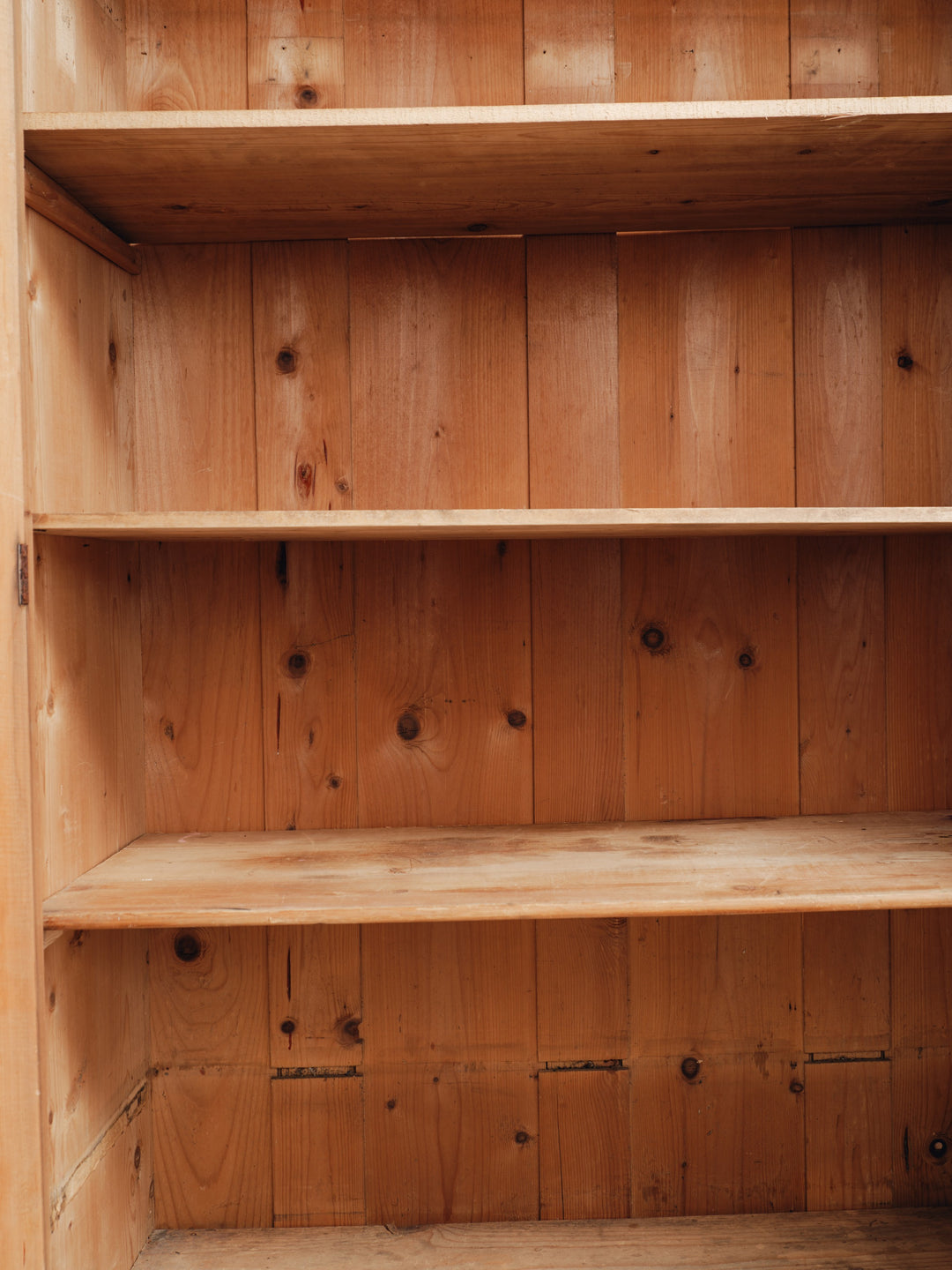 the inside of a wooden cabinet with empty shelves .