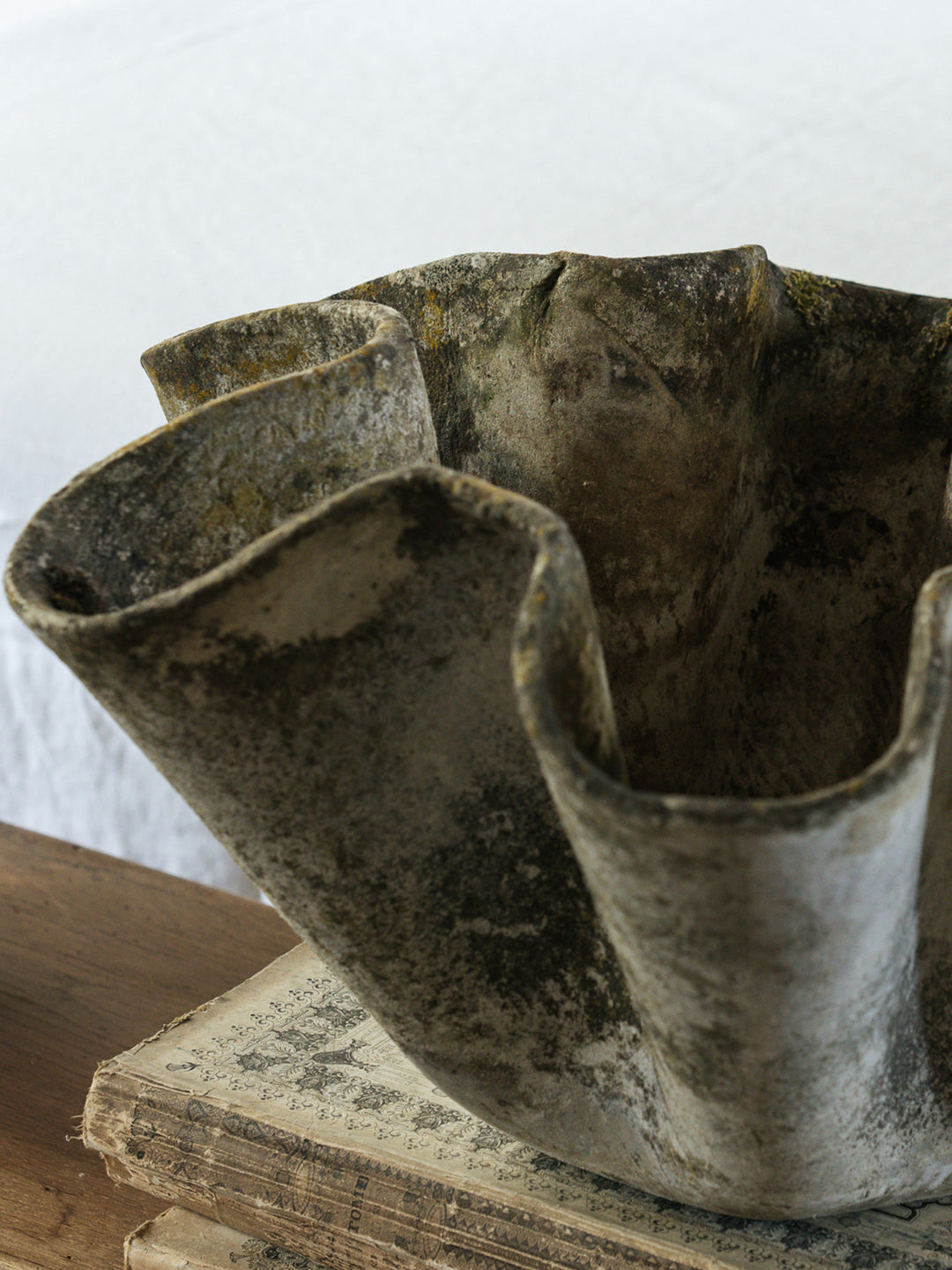 a very old looking bowl is sitting on top of a stack of books