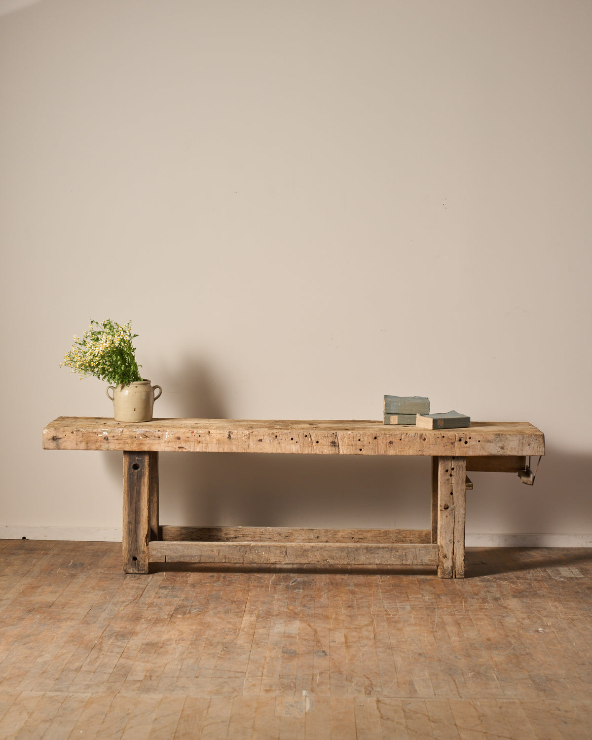 Rustic wooden workbench with a jug of white flowers and two books.