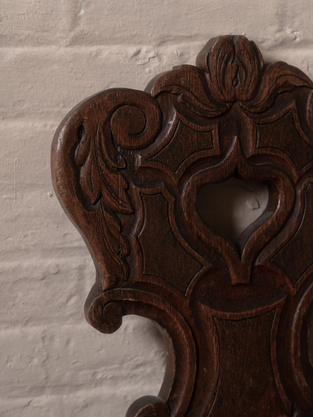 a carved piece of wood is against a white brick wall
