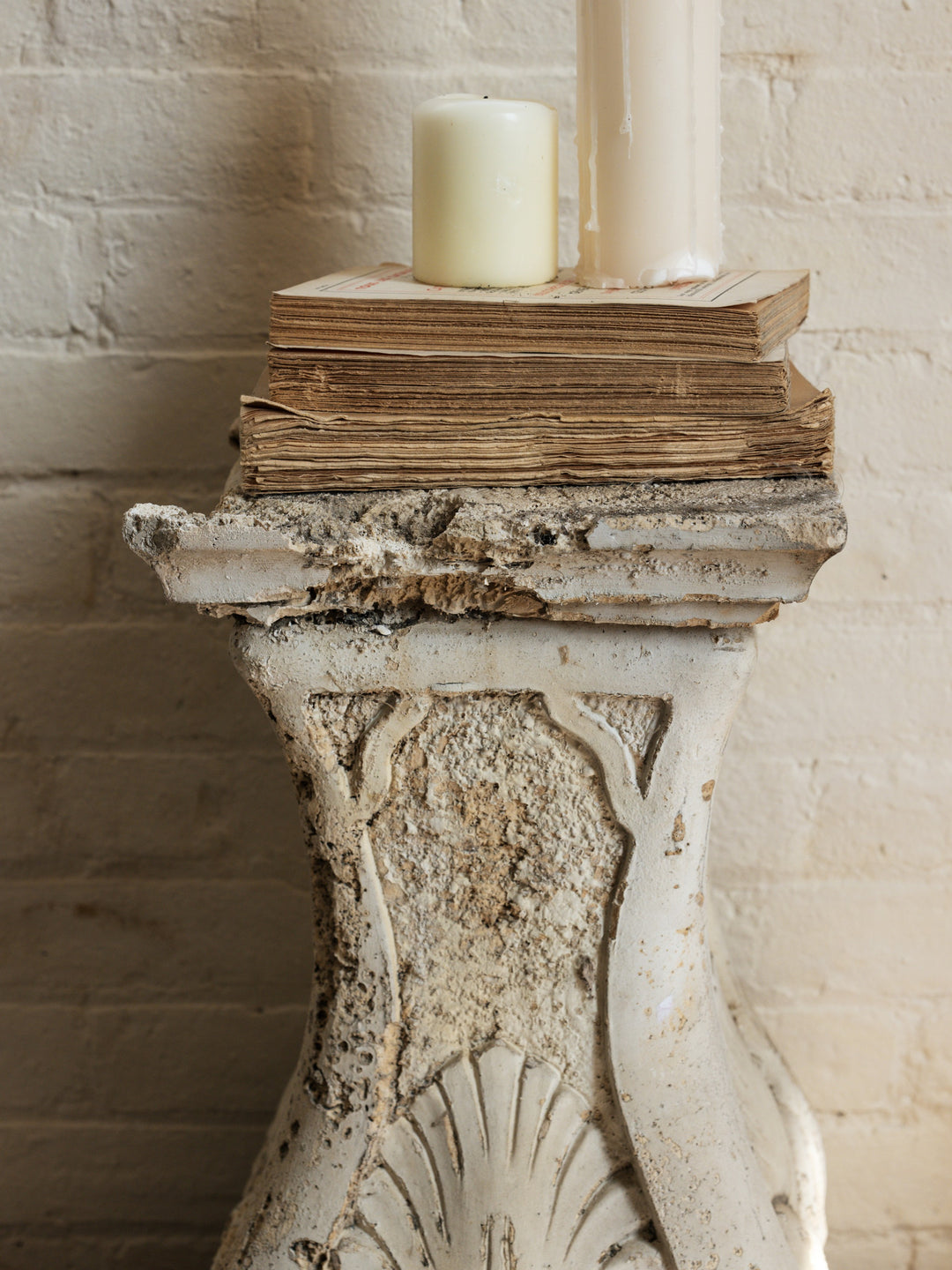 a stack of books and a candle on top of a pedestal