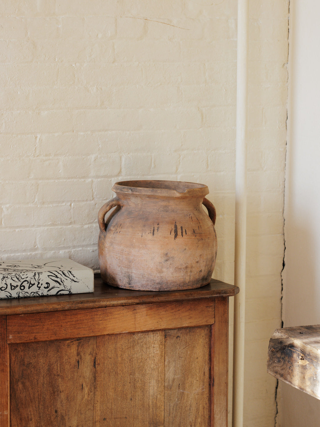 a large pot sits on a wooden table next to a book