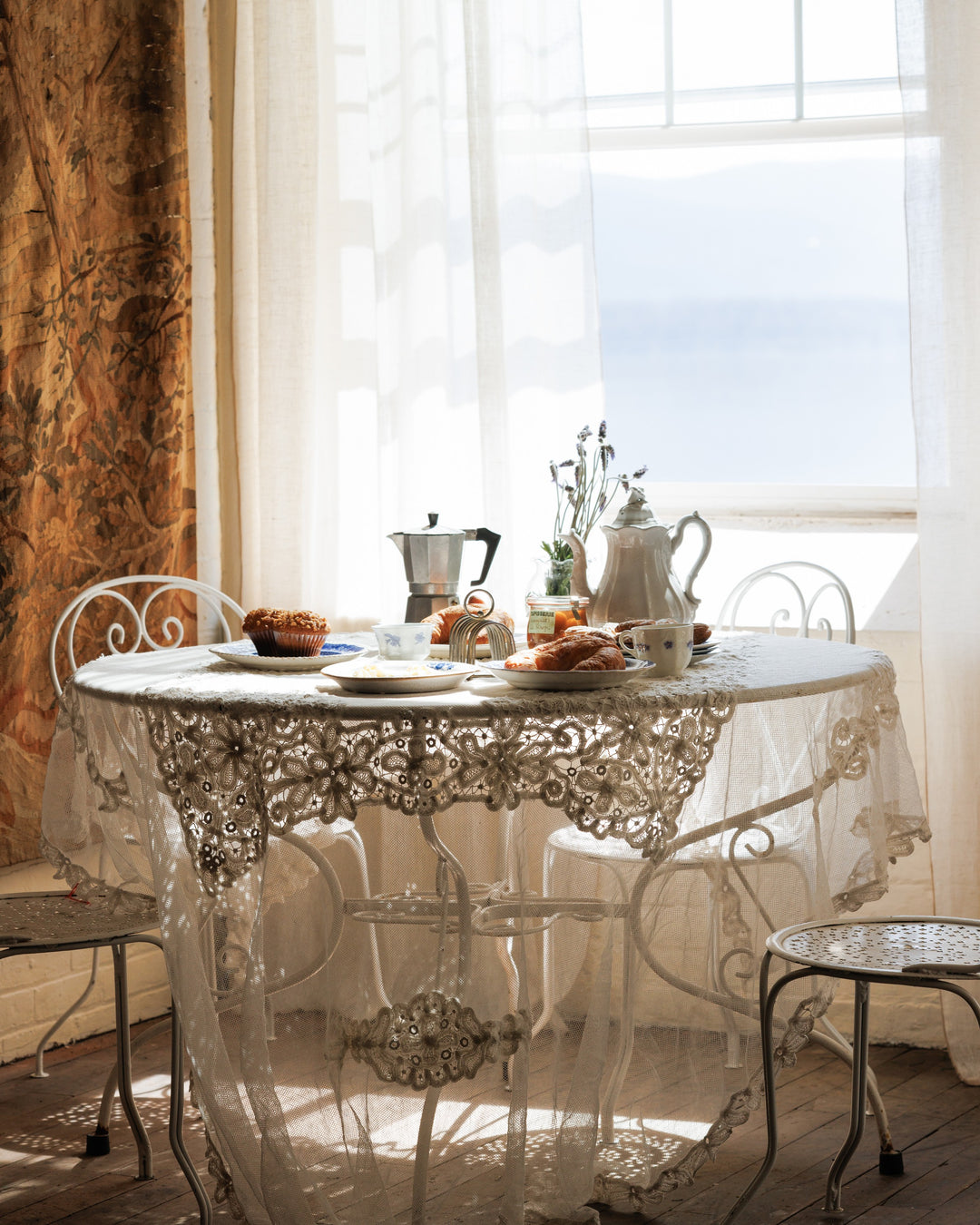 a table with a lace tablecloth and a coffee pot on it