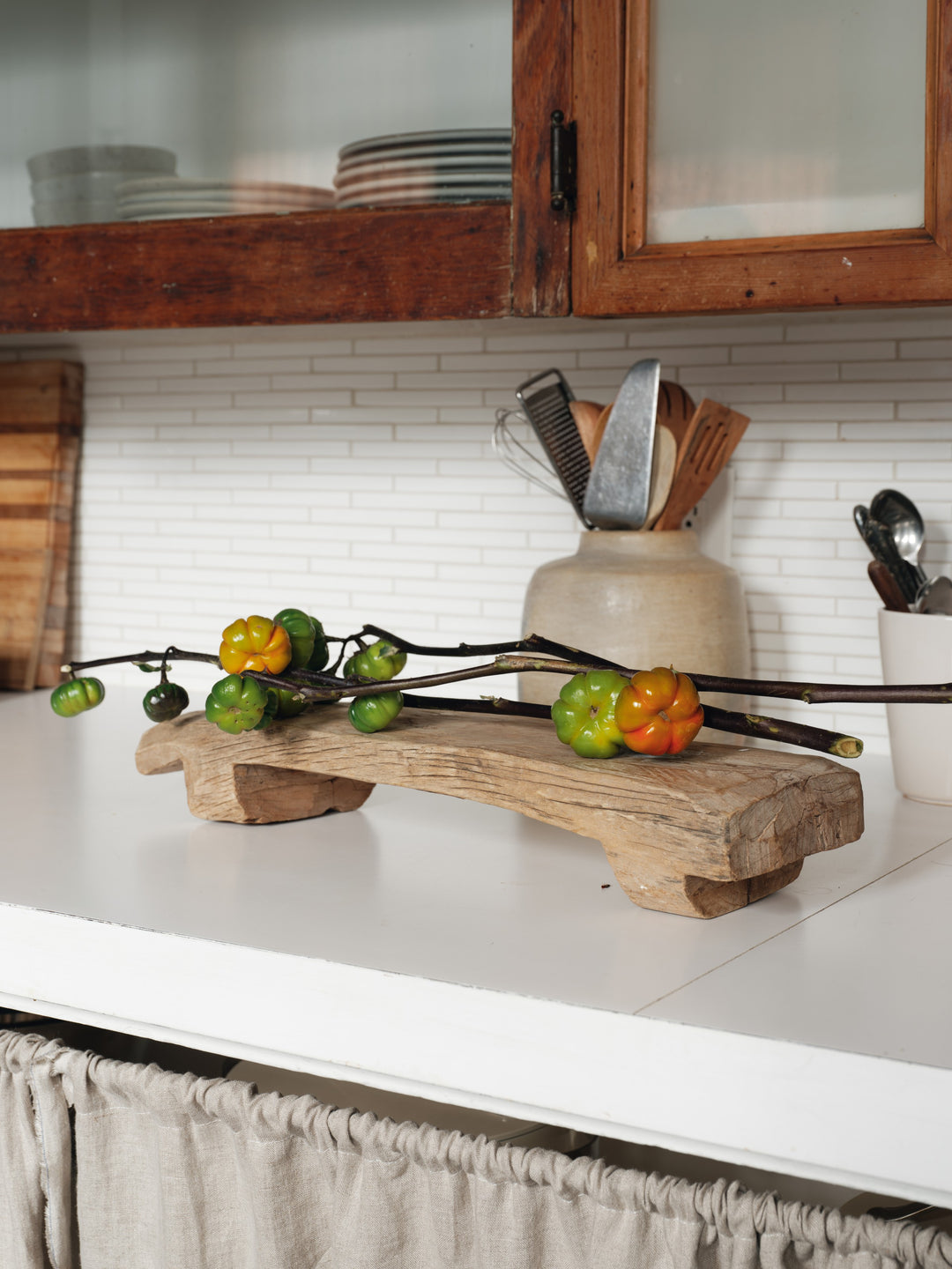 a wooden tray with tomatoes on it sits on a kitchen counter