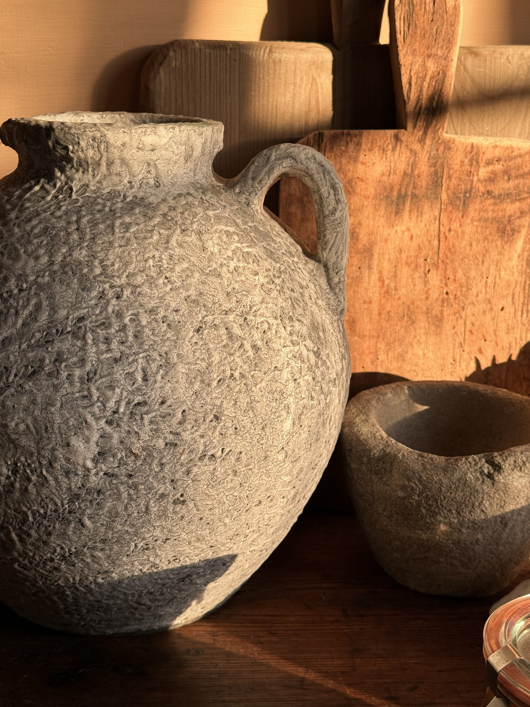 a large gray vase with a handle sits on a wooden table