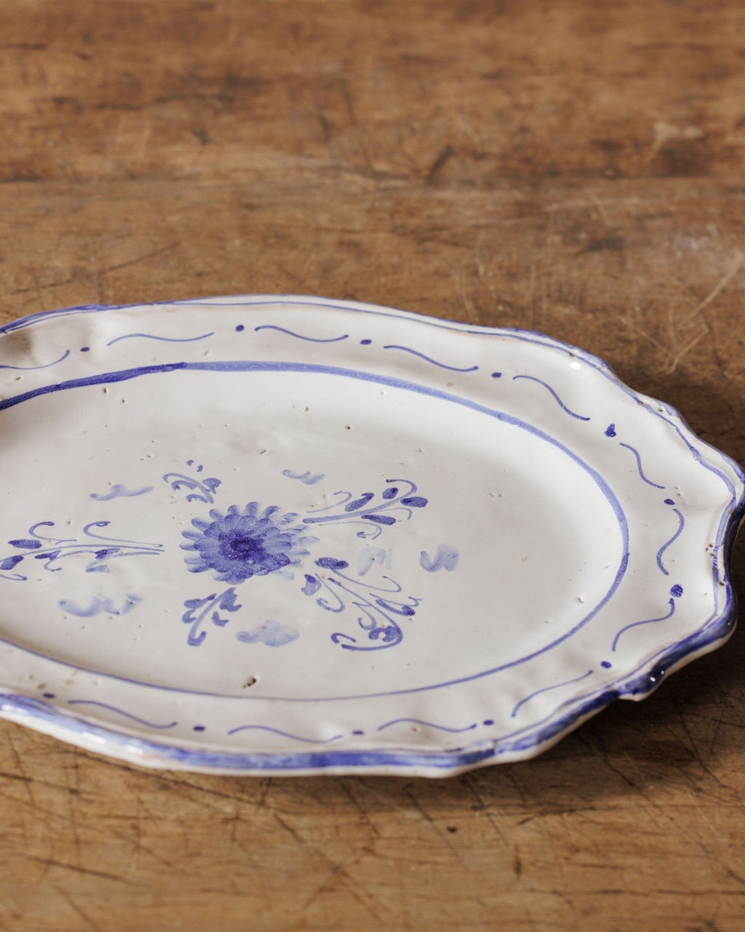 White oval platter with blue hand-painted floral design on a wooden surface.