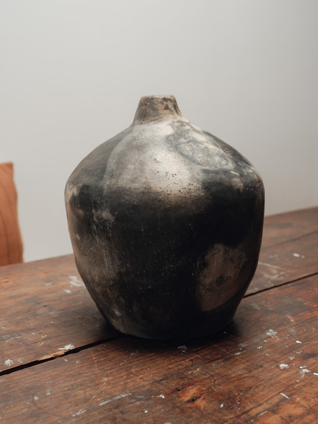 a large black vase sits on a wooden table
