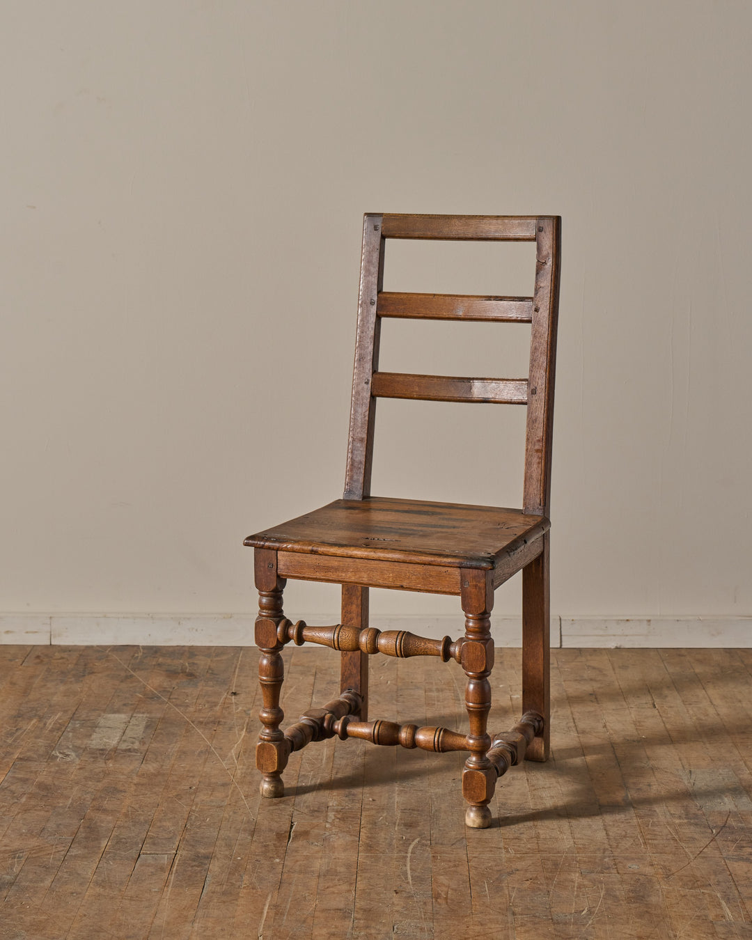 An antique wooden chair with a slat back and turned legs.