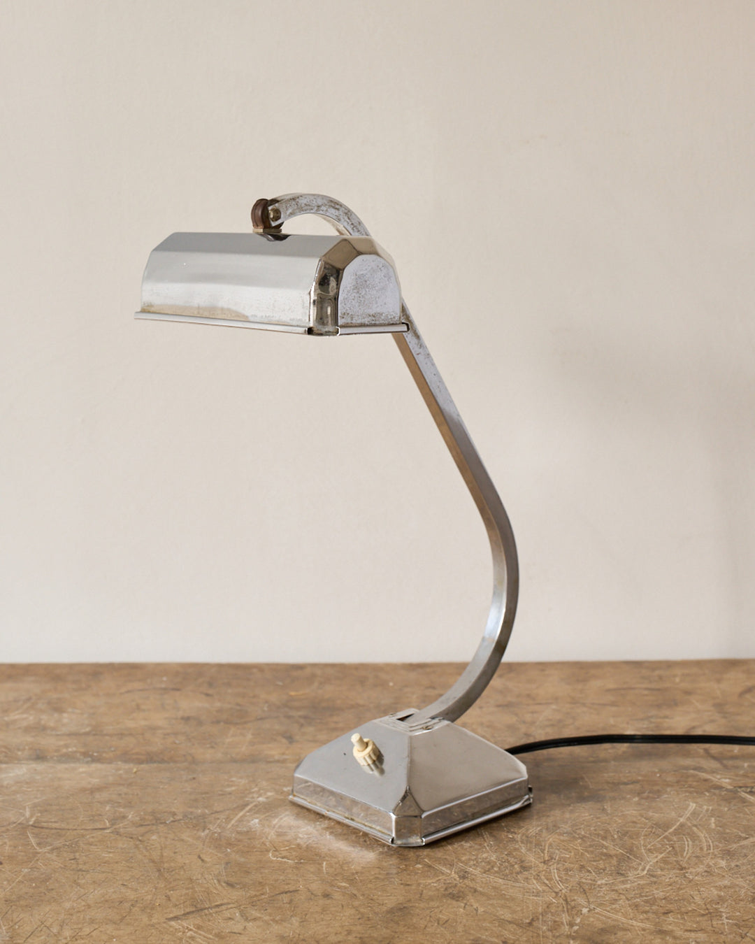A vintage chrome desk lamp with a rectangular shade and curved arm.