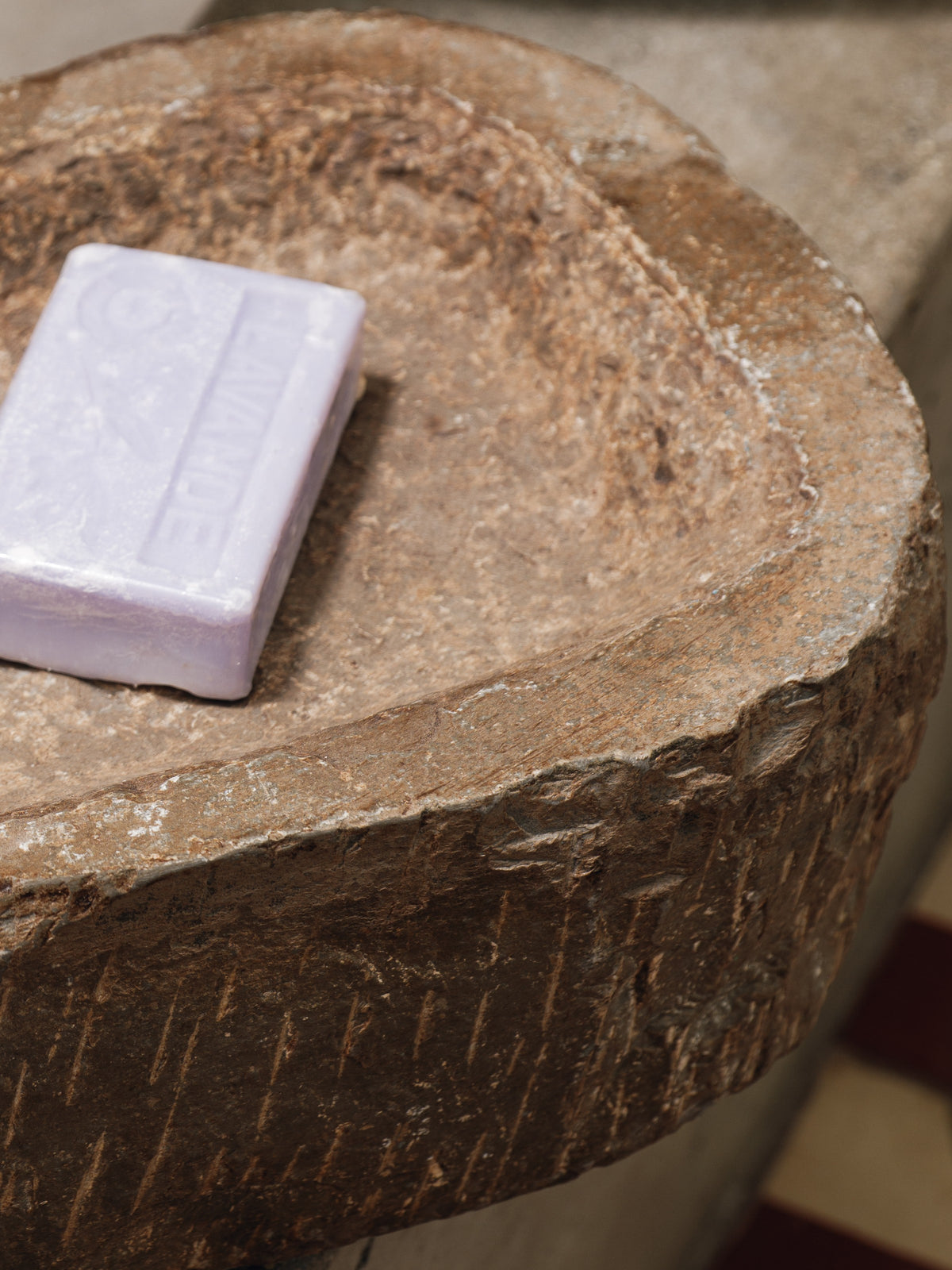 a purple bar of soap is sitting on a rock