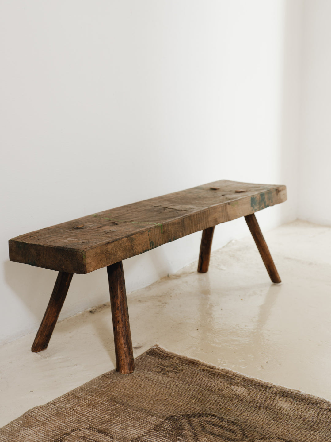 a wooden bench is sitting in a room next to a rug