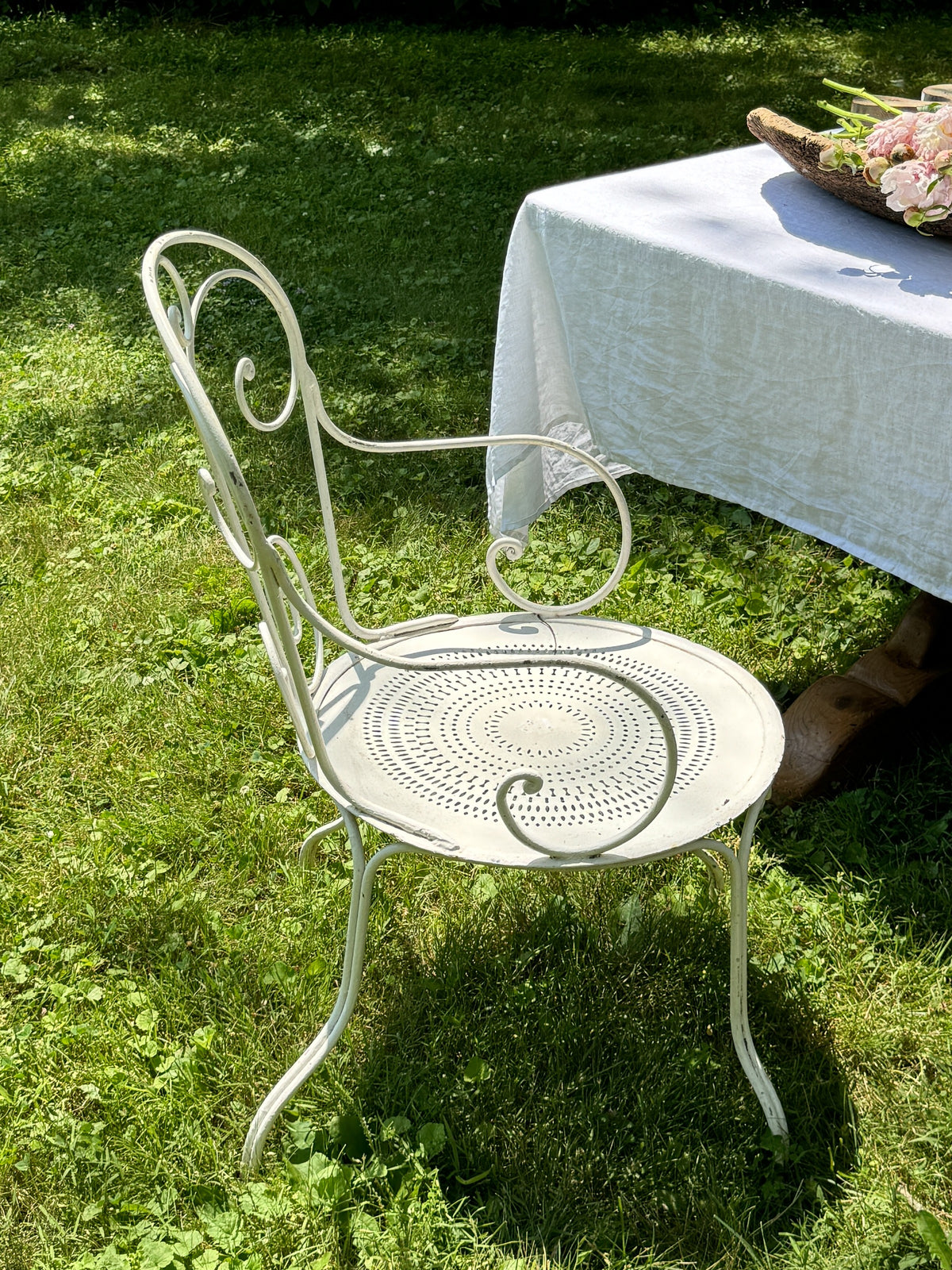 a white chair is sitting in the grass next to a table .