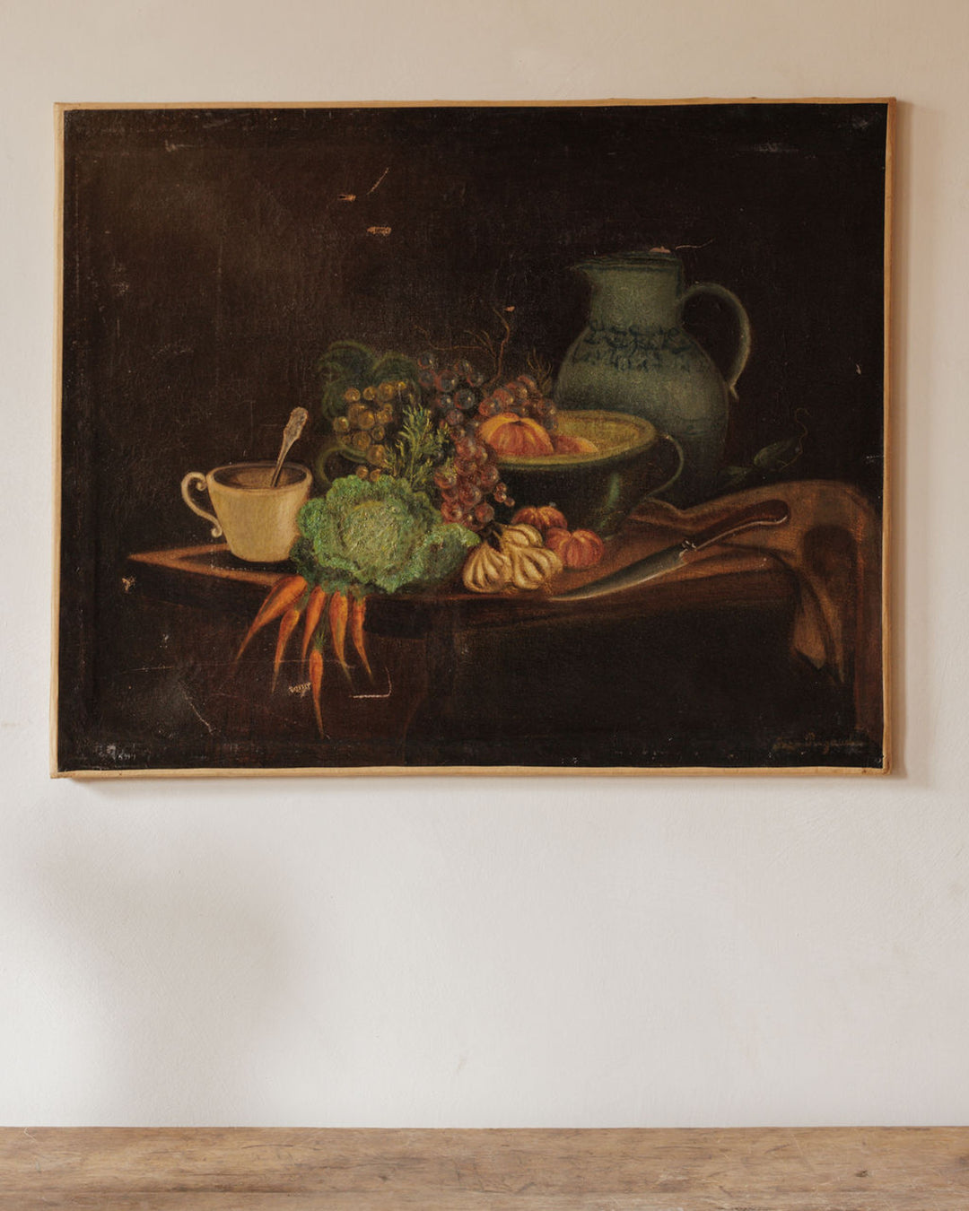 Dark still life painting of a pitcher, fruit, and vegetables on a table.