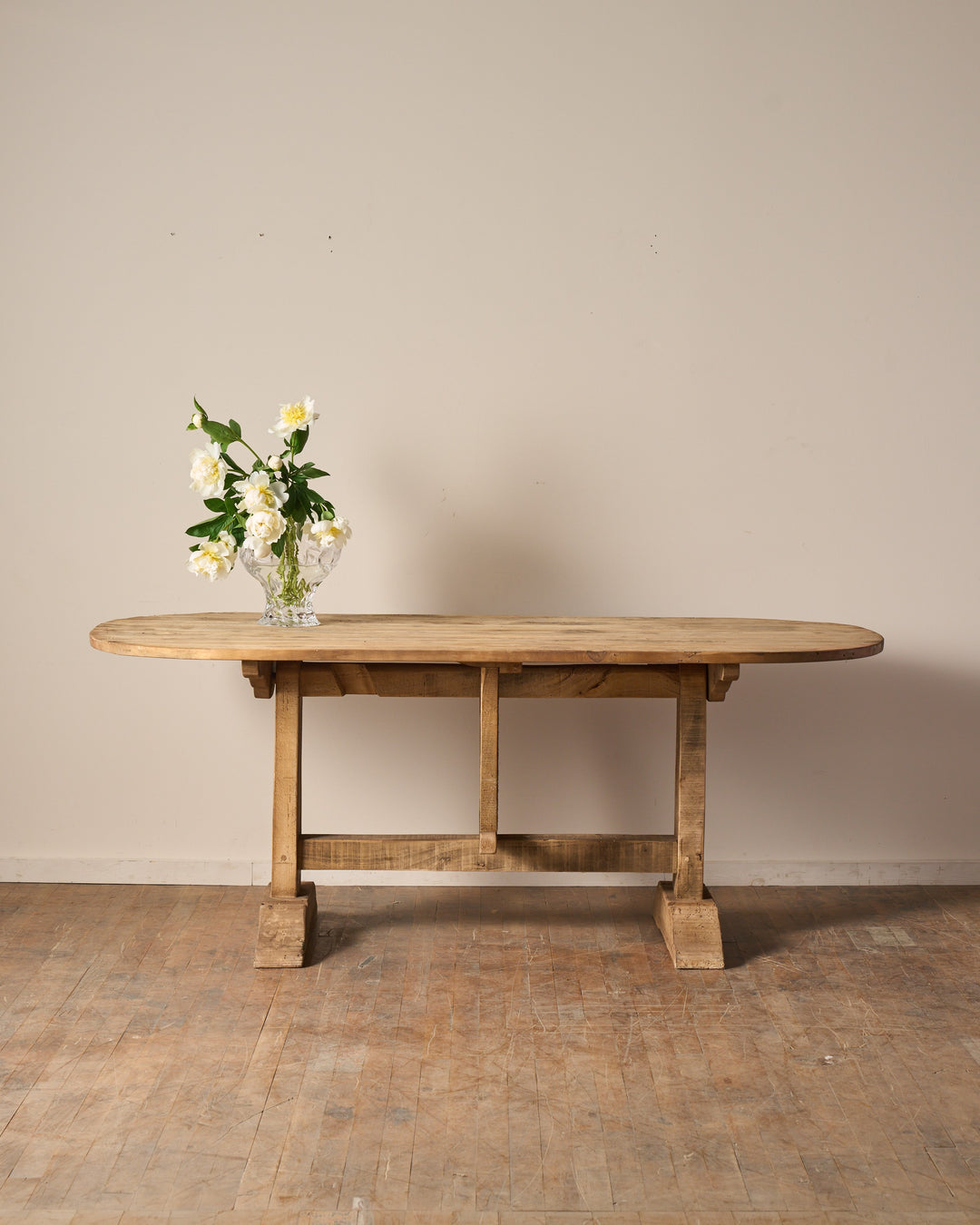 Rustic oval wooden table with white flowers in a vase.