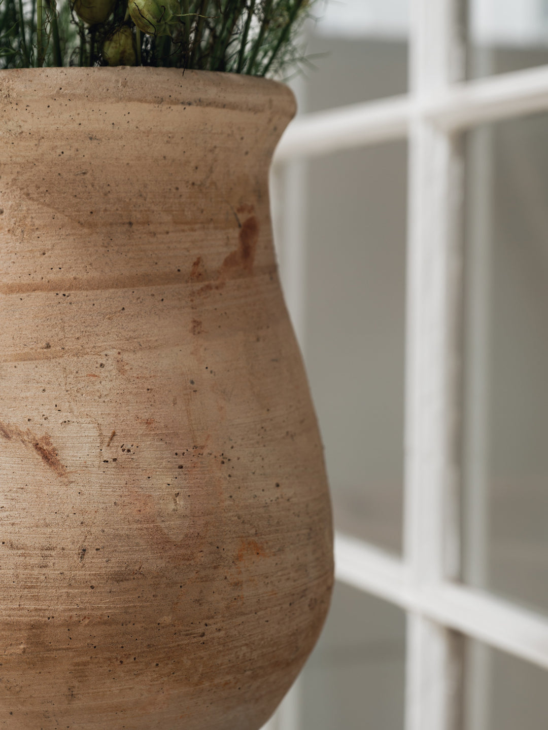 a large clay pot with a plant in it is hanging from a window .