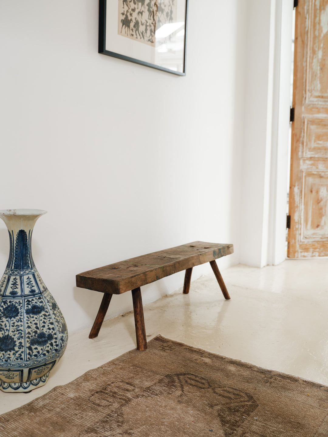 a blue and white vase sits next to a wooden bench