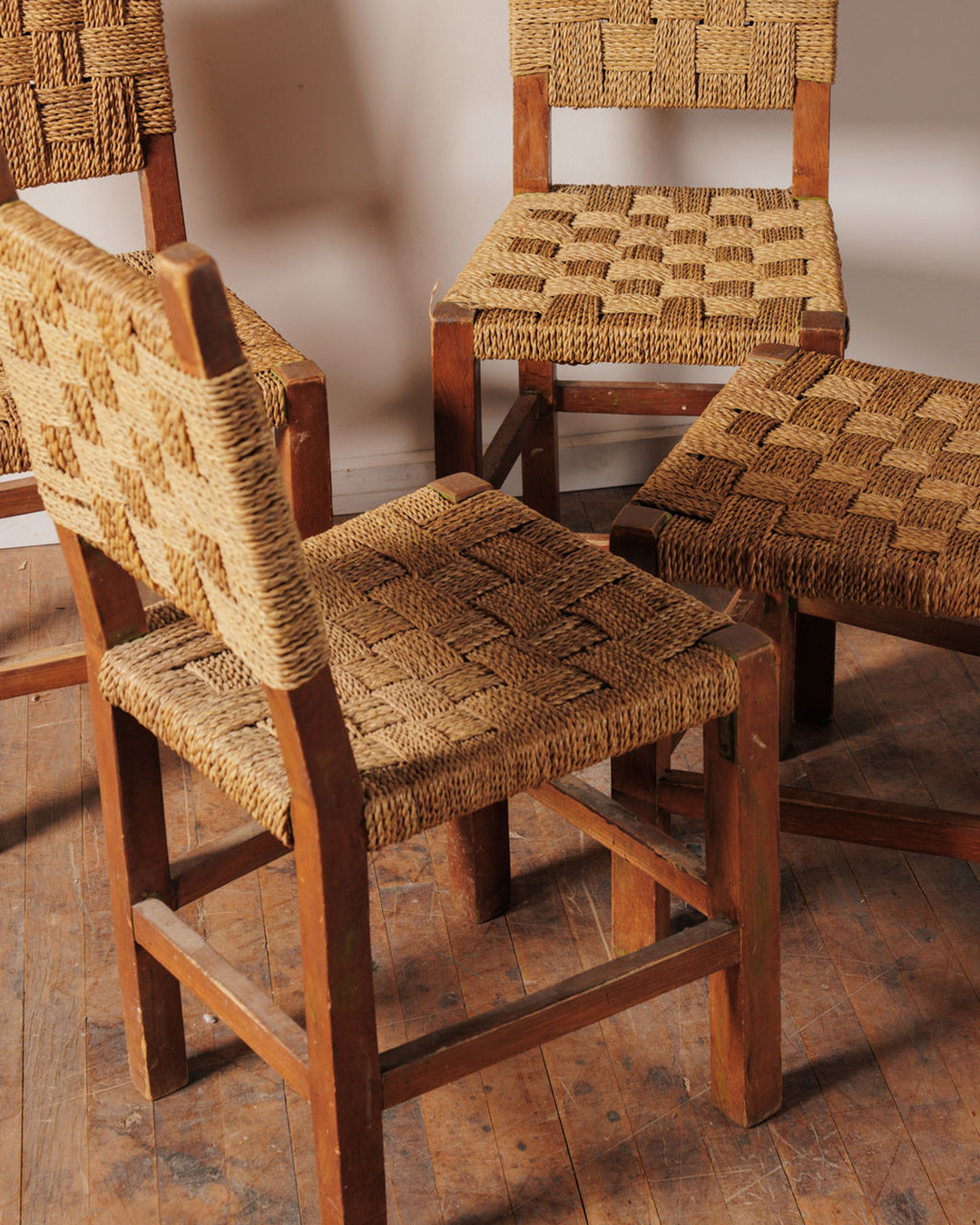 Four chairs with dark wooden frames and woven rush seats and backs.