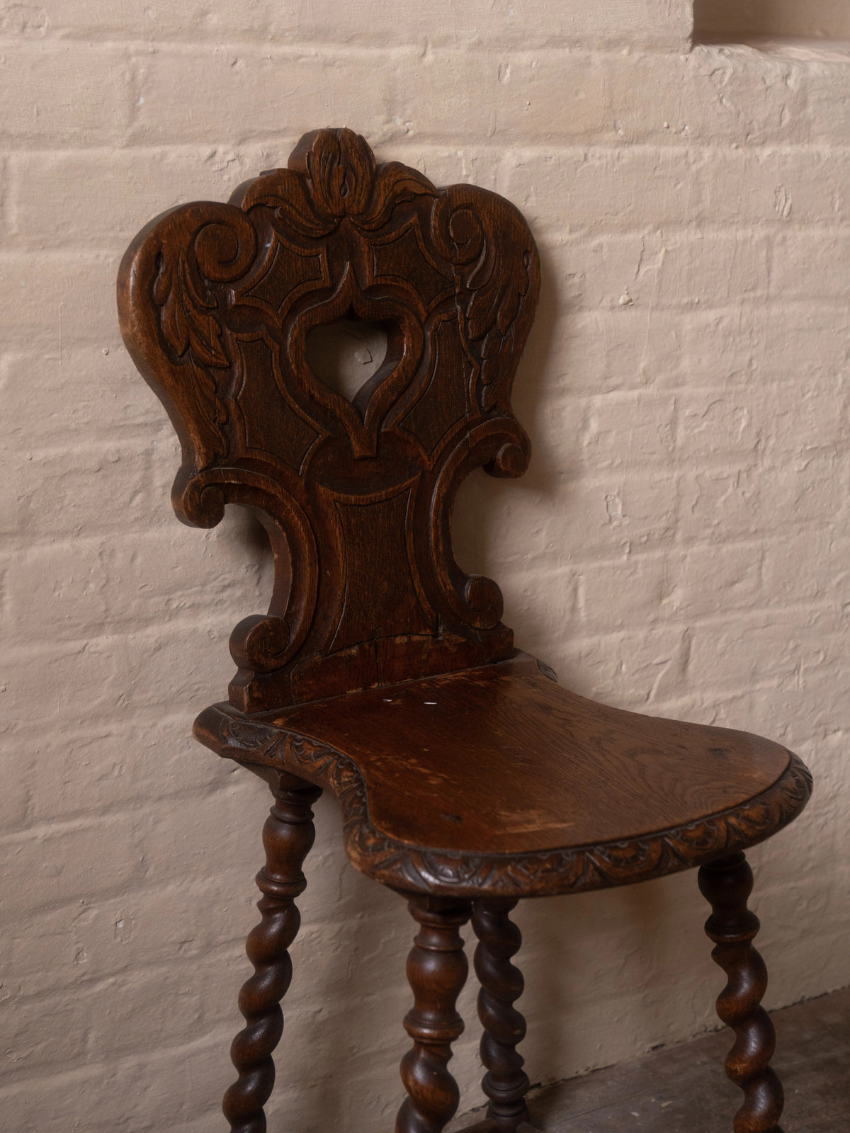 a wooden chair is against a white brick wall