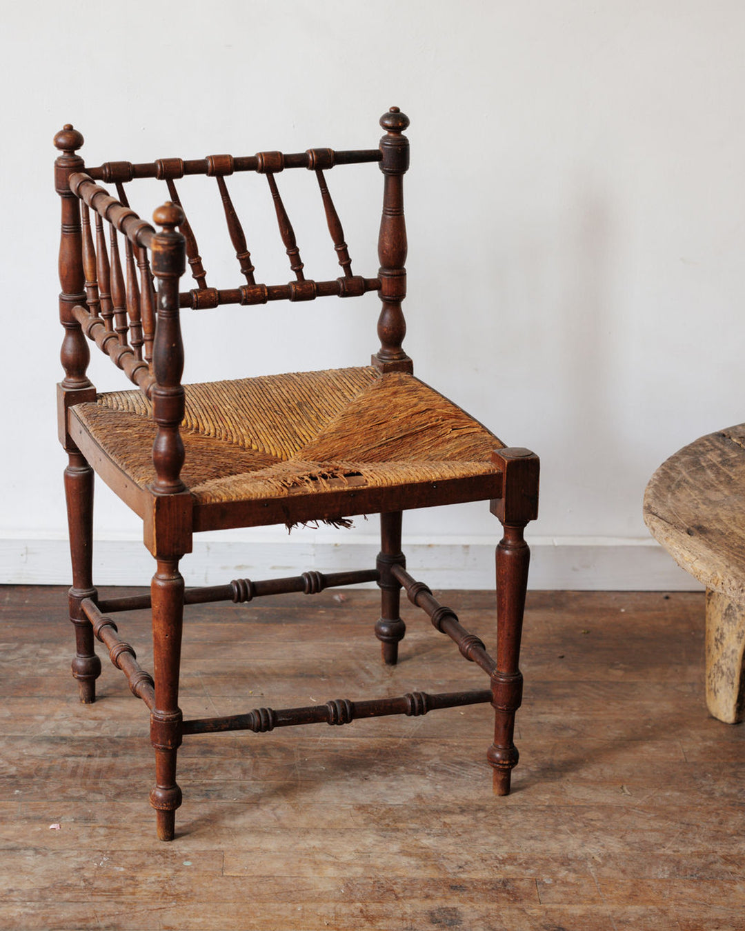 Antique dark wood corner chair with a woven rush seat.