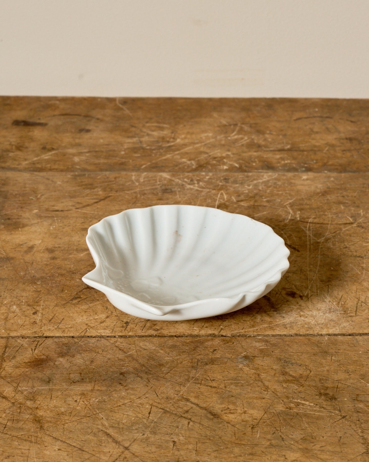White shell-shaped dish on a wooden surface.