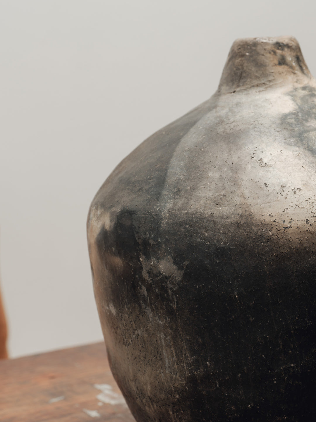 a black vase is sitting on a wooden table .