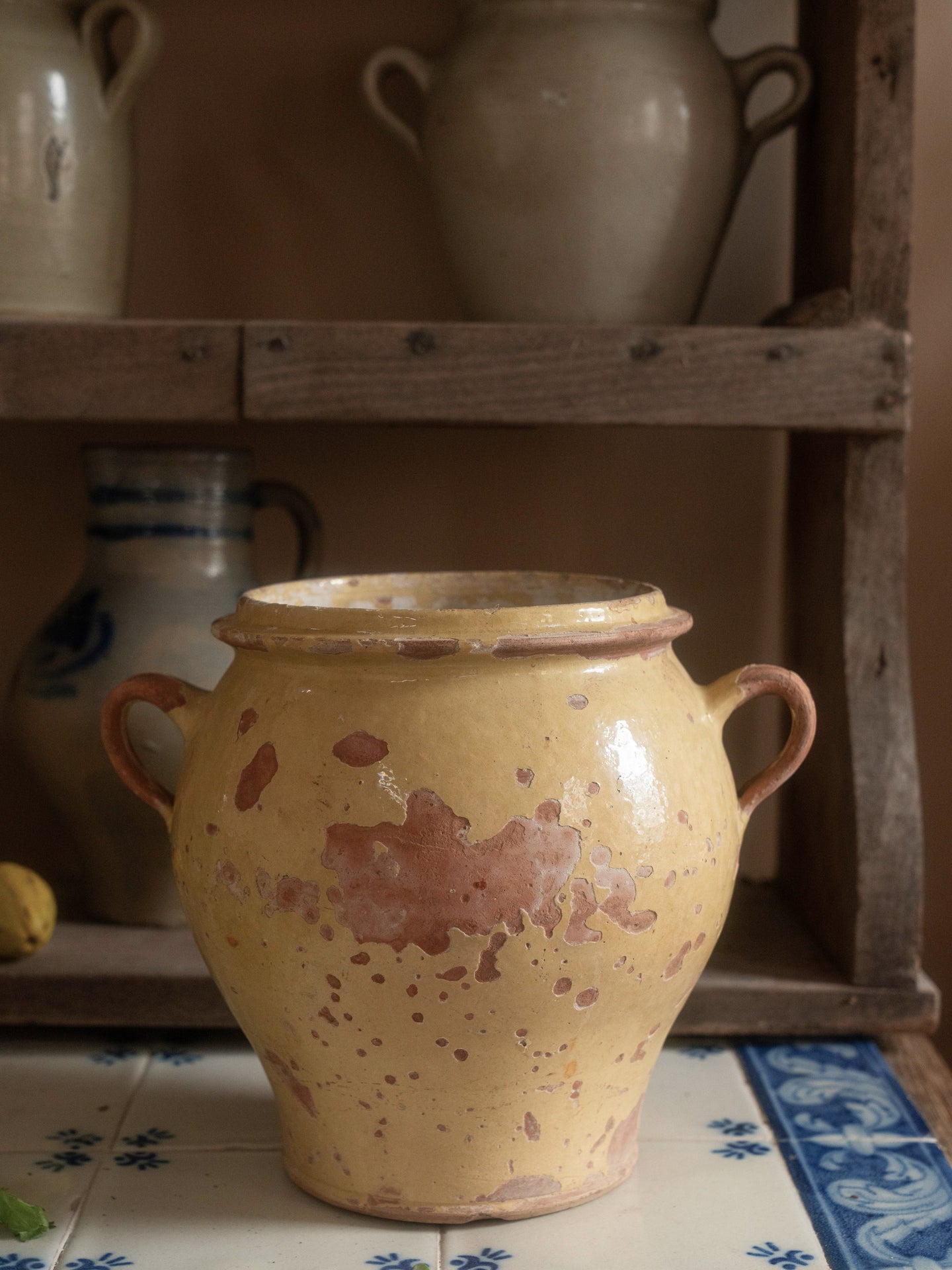 a yellow pot with two handles is sitting on a tiled counter top .