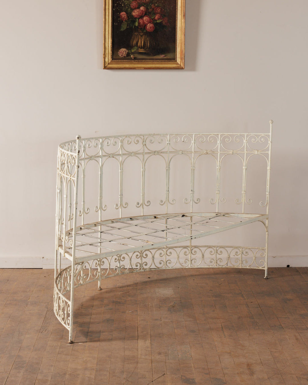 White curved ornate wrought iron bench with a floral painting above.