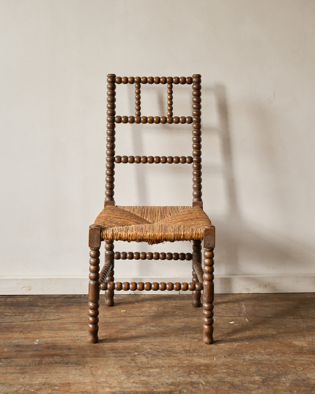A bobbin-turned wooden chair with a woven rush seat.