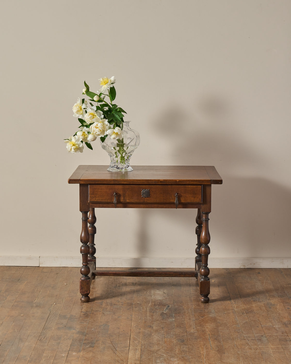 Antique wooden table with white peonies in a glass vase.