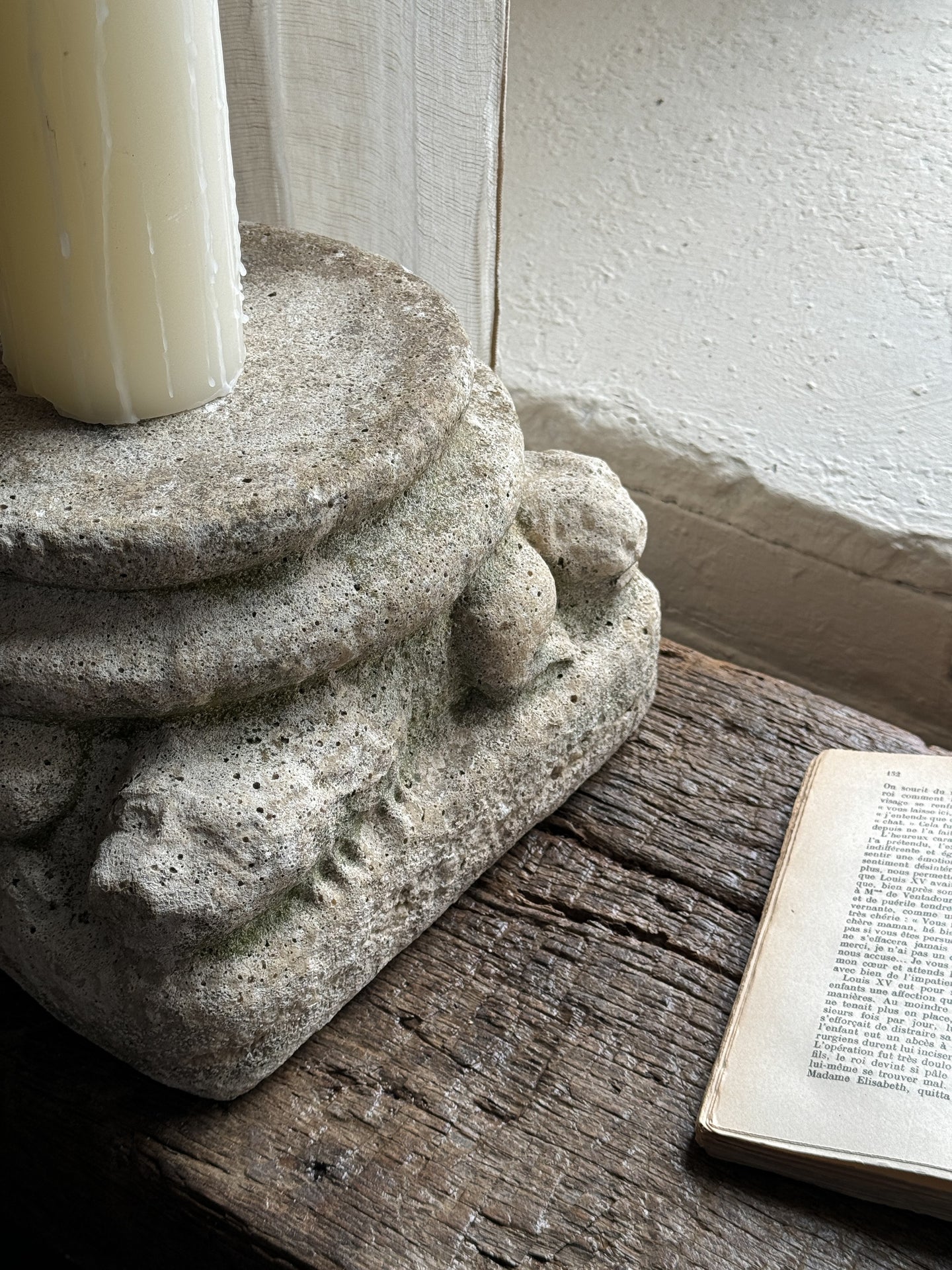 a stone candle holder is sitting on a wooden table next to a book .