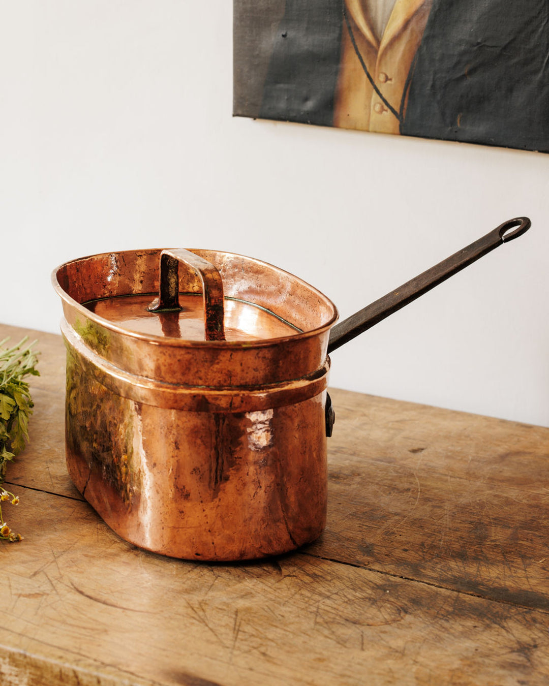 Antique oval copper fish kettle on a rustic wooden table.
