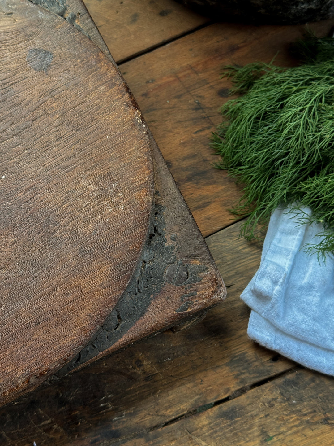 a wooden cutting board is sitting on a wooden table next to some dill .